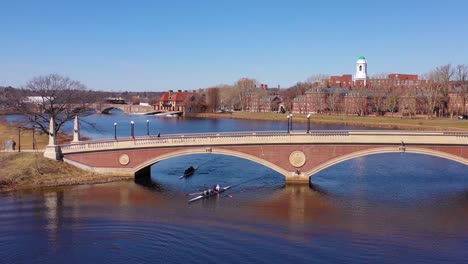 Aerial-over-the-John-W-Weeks-Footbridge-reveals-Harvard-University-campus-on-the-Charles-River-with-rowing-crew
