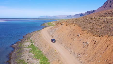 Aerial-over-a-black-van-traveling-on-a-dirt-road-in-Iceland-near-Raudisandur-Beach-in-the-Northwest-Fjords-2