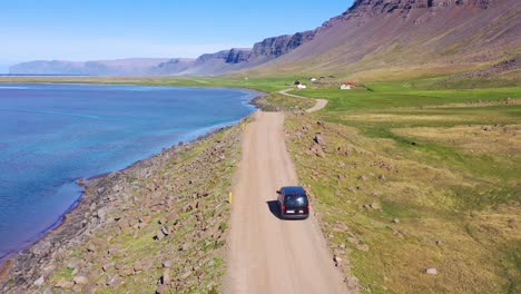 Aerial-over-a-black-van-traveling-on-a-dirt-road-in-Iceland-near-Raudisandur-Beach-in-the-Northwest-Fjords-4