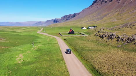 Aerial-over-a-black-van-traveling-on-a-dirt-road-in-Iceland-near-Raudisandur-Beach-in-the-Northwest-Fjords-6