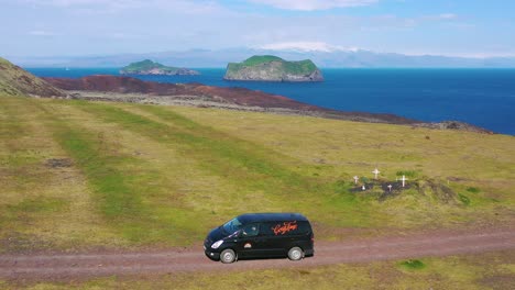 Aerial-over-a-black-camper-van-traveling-on-a-dirt-road-in-Iceland-in-the-Westmann-islands-1