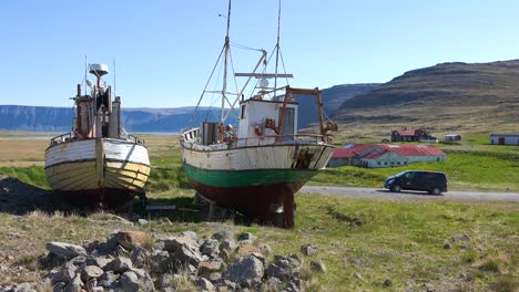 A-camper-van-drives-past-landlocked-fishing-boats-in-the-remote-Westfjords-of-Iceland