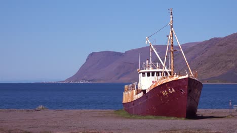 Un-Barco-De-Pesca-Abandonado-Se-Sienta-En-La-Orilla-De-Los-Fiordos-Del-Oeste-Islandia-3