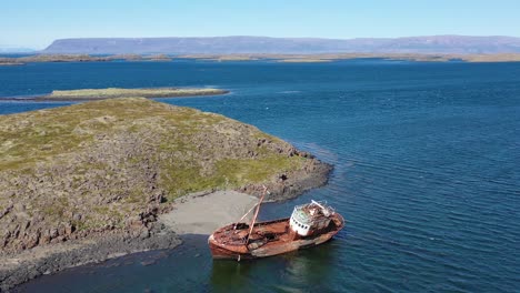 Aerial-over-abandoned-fishing-boat-sitting-on-the-shore-of-the-Westfjords-Iceland