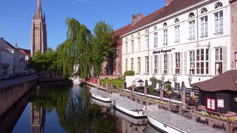 Nice-establishing-shot-of-a-canal-and-boats-and-church-in-Bruges-Belgium