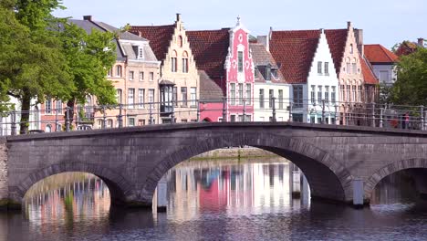 Pretty-establishing-shot-of-a-bridge-canal-in-Bruges-Belgium-with-man-on-bicycle-crossing