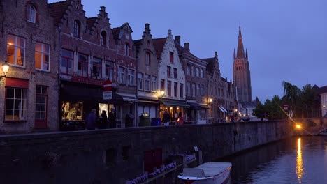 Calle-De-Tiendas-Y-Canal-Por-La-Noche-En-Brujas,-Bélgica