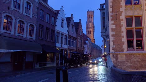 Street-of-shops-restaurants-and-horse-cart-at-night-in-Bruges-Belgium