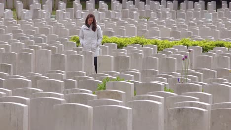 A-woman-in-a-white-coat-looks-at-headstones-of-the-Etaples-France-World-War-cemetery-military-graveyard-1