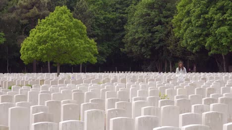 A-ghost-woman-in-a-white-coat-looks-at-headstones-of-the-Etaples-France-World-War-cemetery-military-graveyard-then-slowly-dissolves-and-disappears