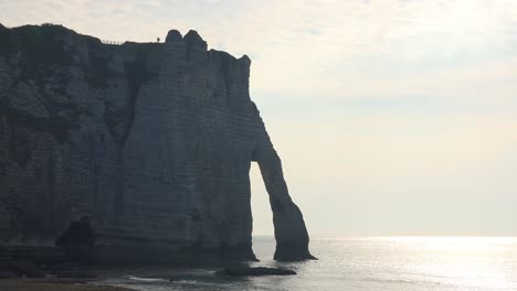 A-couple-stands-on-the-white-limestone-cliffs-and-arches-at-Etretat-France-English-Channel