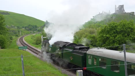 An-old-steam-train-passes-the-ruins-of-Corfe-Castle-Dorset-England