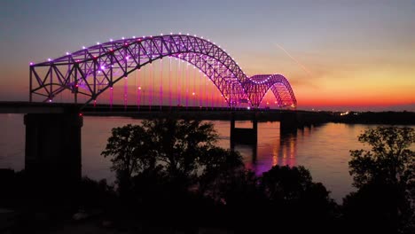Good-rising-evening-night-aerial-of-Memphis-Hernando-De-Soto-Bridge-with-colorful-lights-and-Mississippi-River