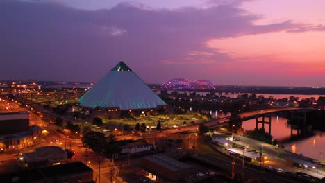 Beautiful-night-aerial-shot-of-the-Memphis-pyramid-Hernando-De-Soto-Bridge-and-cityscape-at-dusk