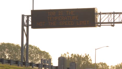 A-humorous-highway-sign-on-a-hot-day-says-100-degrees-is-the-temperature-not-the-speed-limit