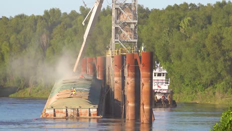 Workers-load-a-grain-barge-along-the-Mississippi-River-while-a-tugboat-arrives-nearby-1