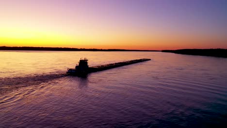 Very-good-aerial-of-a-tugboat-pushing-a-barge-up-the-Mississippi-River-near-Memphis-Tennessee-at-sunset-or-dusk