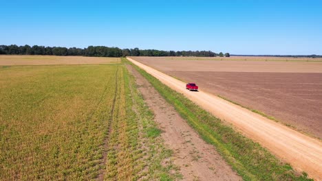 Aerial-shot-of-a-red-pickup-truck-traveling-on-a-dirt-road-in-a-rural-farm-area-of-Mississippi-3