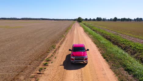Vista-Aérea-shot-of-a-red-pickup-truck-traveling-on-a-dirt-road-in-a-rural-farm-area-of-Mississippi-6