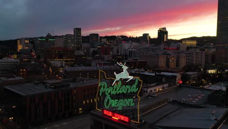 Moody-aerial-around-Portland-Oregon-stag-deer-sign-and-downtown-old-town-cityscape-and-business-district-at-sunset-or-dusk