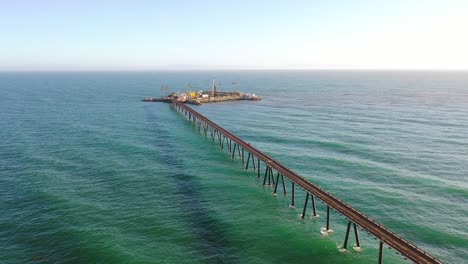 Aerial-over-a-long-oil-pier-extending-to-a-small-island-off-the-shore-of-Mussel-Shoals-Rincon-Beach-Santa-Barbara-California-1