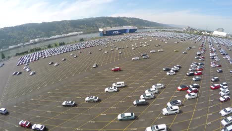 An-aerial-over-vast-mostly-empty-parking-lots-at-a-shipping-container-port-importing-cars