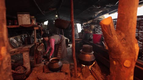 Una-Mujer-Cocina-Sobre-Un-Fuego-Abierto-Dentro-De-Su-Casa-En-El-Tíbet-O-Nepal-1
