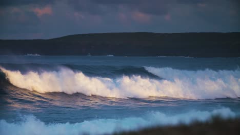 Waves-crash-against-a-rocky-shore-in-golden-light