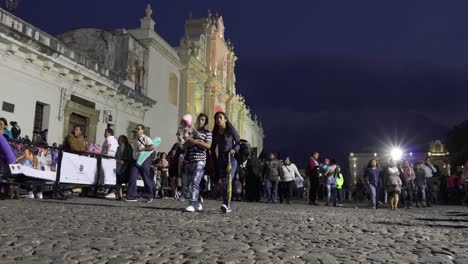POV-shot-of-people-walking-at-night-along-a-busty-street-in-front-of-the-cathedral-in-Antigua-Guatemala