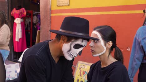 A-man-paints-a-woman's-face-for-the-day-of-the-dead-in-San-Miguel-De-Allende-Mexico