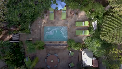 Drone-shot-of-a-luxurious-pool-surrounded-by-palm-trees-at-the-Biltmore-Hotel-in-Montecito