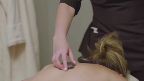 A-masseuse-uses-heated-stones-during-the-massage-of-a-female-client