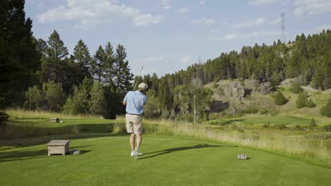A-male-golfer-hits-a-short-iron-off-a-par-three-hole-at-an-exclusive-course-in-Montana