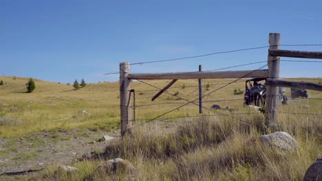 Two-ATVs-pass-through-a-gate-on-a-ranch-road-in-central-Montana