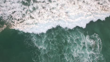 A-rising-aerial-perspective-looking-straight-down-at-the-ocean-with-waves-rolling-in