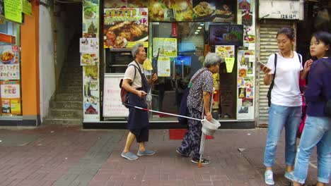 A-poor-handicapped-homeless-blind-man-musician-is-led-by-his-wife-down-a-street-in-Hong-Kong-China-1