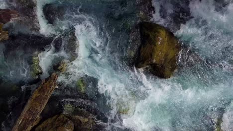 A-high-angle-rising-aerial-over-a-fast-flowing-river-in-a-forest