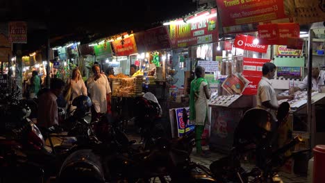 Un-Hombre-Y-Una-Mujer-Caminan-Por-Un-Mercado-Nocturno-En-La-India
