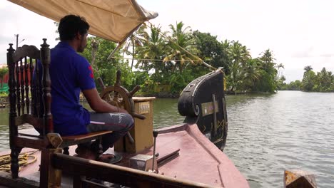A-man-drives-a-houseboat-through-the-backwaters-of-Kerala-India