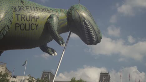 A-Huge-Green-Dinosaur-Doll-Above-Huge-Crowds-Of-Protesters-Gathering-On-The-Streets-Of-London-To-Protest-The-Visit-Of-US-President-Donald-Trump