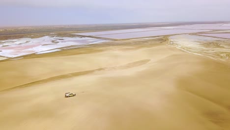 Aerial-over-a-4WD-safari-jeep-vehicle-driving-across-the-sand-dunes-of-Namibia-Africa