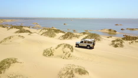 Aerial-over-a-4WD-safari-jeep-vehicle-driving-across-the-sand-dunes-and-Skeleton-Coast-of-Namibia-Africa