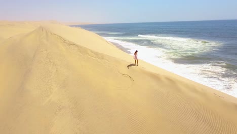 Aerial-over-a-model-released-woman-walking-on-magnificent-sand-dunes-on-the-Skeleton-Coast-Namibia