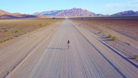 Antenne-über-Eine-Frau,-Die-Auf-Einem-Feldweg-In-Der-Namib-Wüste-In-Namibia-Afrika-Joggt-Oder-Läuft