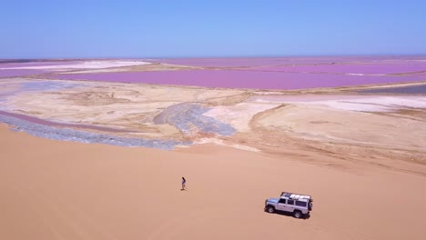 Erstaunliche-Antenne-über-Einer-Frau,-Die-Auf-Einer-Farbenfrohen-Rosa-Salzseeregion-In-Namibia-Afrika-Joggt-Oder-Läuft-3