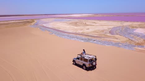 Erstaunliche-Antenne-über-Einer-Frau,-Die-Auf-Einem-4wd-safari-jeep-Auf-Einer-Bunten-Rosa-Salzebenen-Region-In-Namibia-Afrika-Sitzt