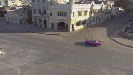 Drone-aerial-of-a-group-of-tourists-riding-in-a-classic-old-car-through-the-streets-of-Havana-Cuba
