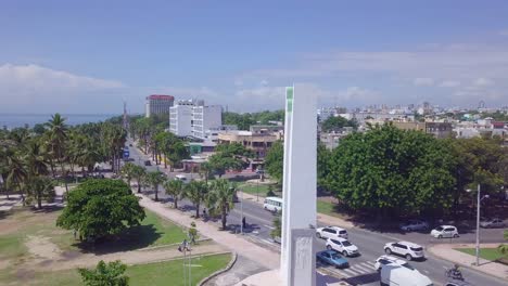Antena-Alrededor-De-Una-Estatua-Con-La-Capital-De-La-República-Dominicana,-Santo-Domingo-En-Segundo-Plano.