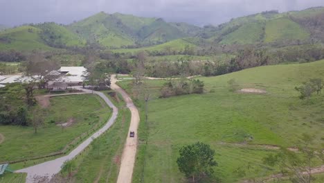 Vista-Aérea-of-a-vehicle-conduciendo-through-the-barren-green-landscapes-of-the-Dominican-Republic