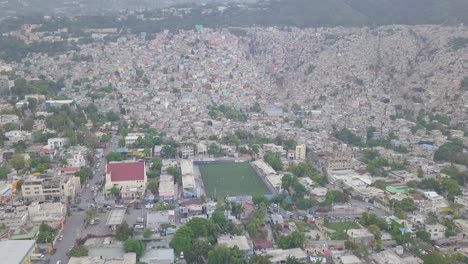 Erstaunliche-Antenne-über-Den-Slums-Favela-Und-Elendsvierteln-Im-Stadtteil-Cite-Soleil-Von-Port-Au-Prince-Haiti-Mit-Fußballstadion-Vordergrund